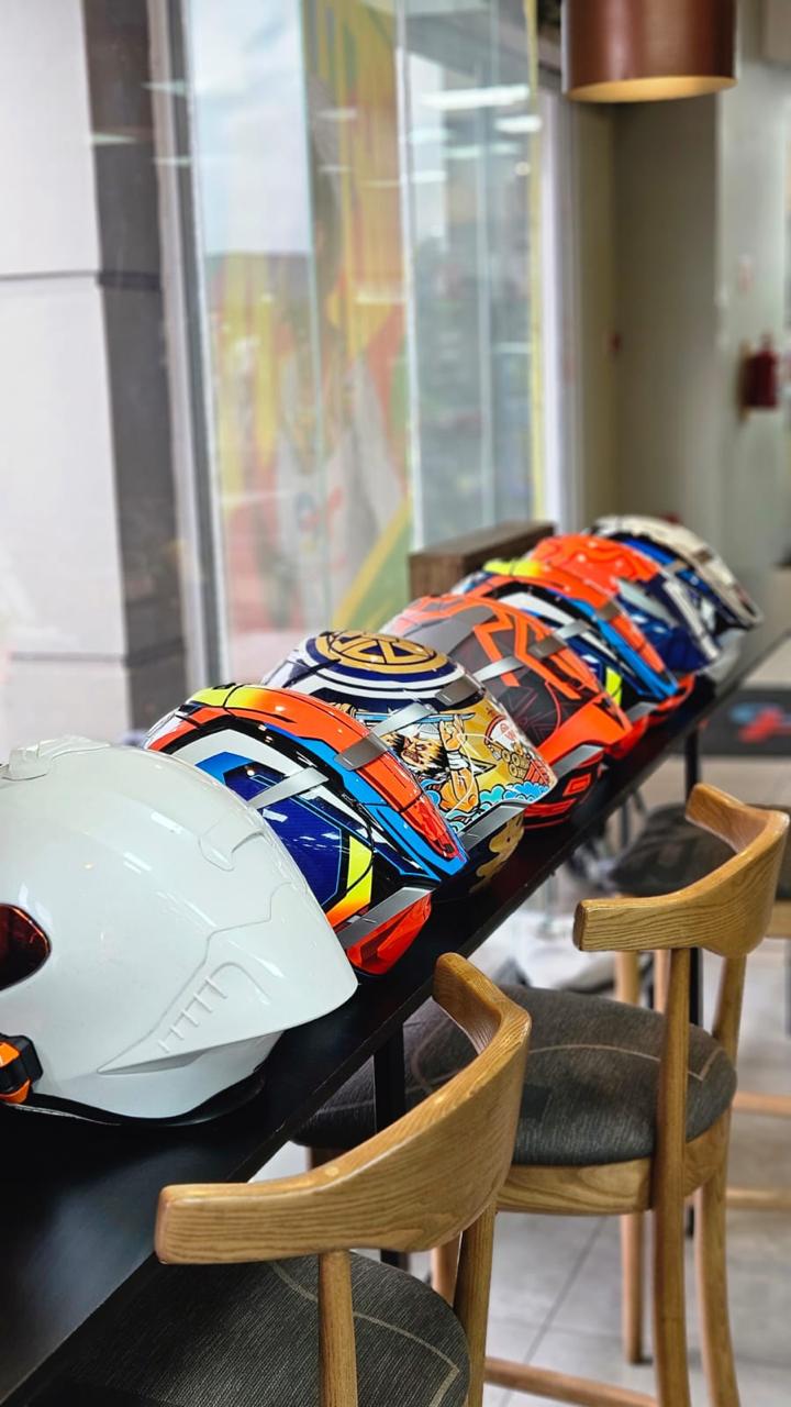 Row of painted racing helmets lined up on a counter